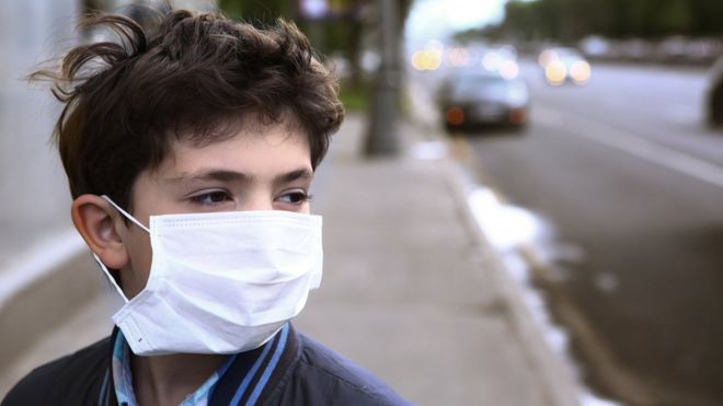 Boy wearing a face mask on a city street