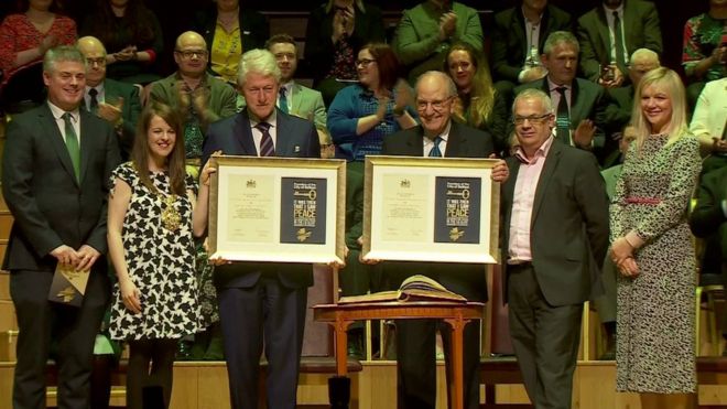 Президент Клинтон и сенатор Митчелл держат свои сертификаты, дающие им свободу города Белфаста