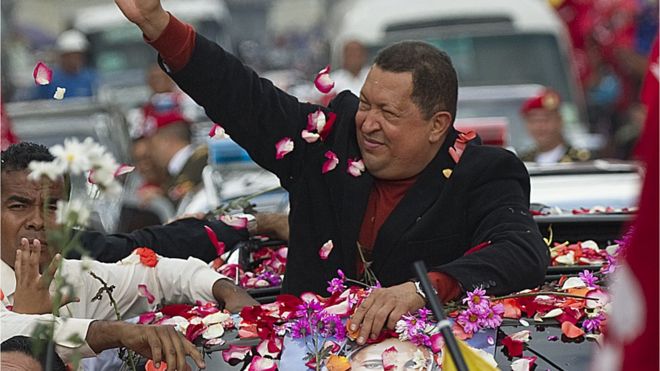 Сторонники Уго Чавеса покрыты лепестками цветов, когда он едет в автомобиле с открытым верхом в 2012 году.
