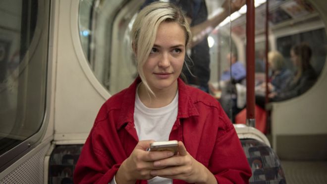 Молодая женщина смотрит со своего мобильного телефона