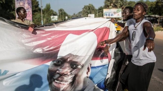 Сторонники новоизбранного президента Гамбии Адамы Барроу сносят плакаты действующего Яхья Джаммеха в Серекунде 2 декабря 2016 года.