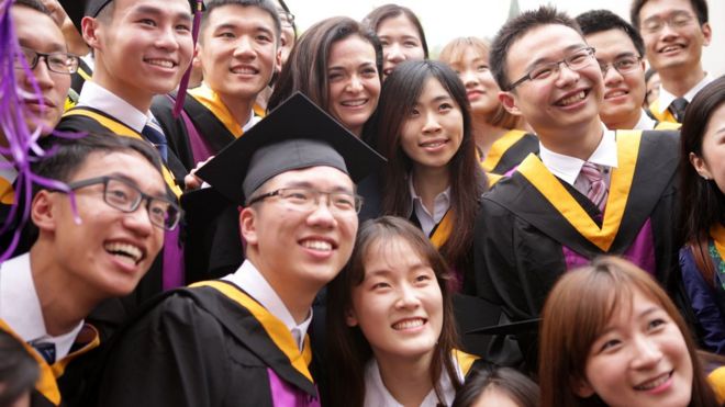 Шерил Сандберг позирует со студентами на выпускной церемонии в Пекине, Китай в 2015 году