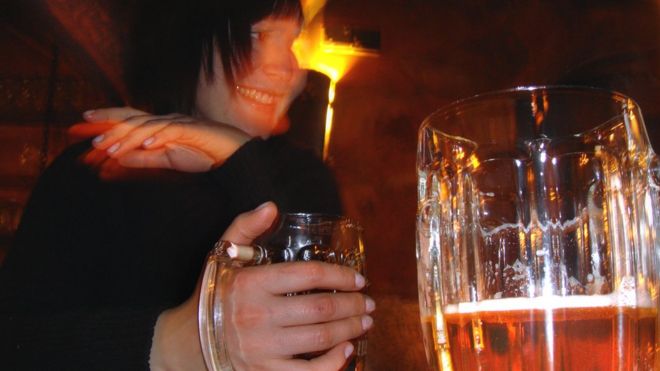 Женщина пьет пиво в московском баре