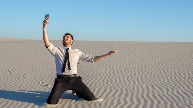 Man in desert searching for mobile phone signal