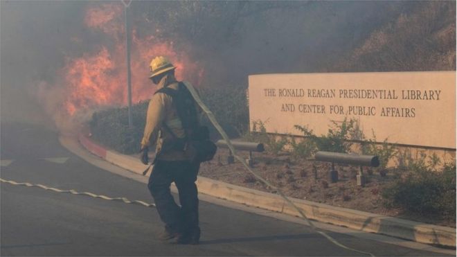 Пожарные сражаются за защиту библиотеки Рейгана от Легкого пожара в Сими-Вэлли, Калифорния, 30 октября 2019 г.
