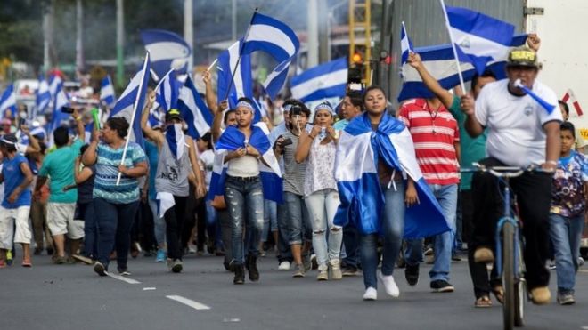 Люди держат никарагуанские флаги во время марша во время акции протеста против правительства президента Никарагуа Даниэля Ортеги, в муниципалитете Никинохомо, Никарагуа, 5 мая 2018 года.