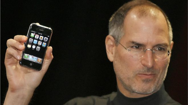 Стив Джобс держит первый iPhone