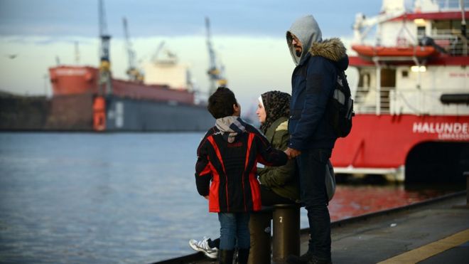 Сирийские беженцы Ваэль Аль-Авис, 31 год, справа, его жена Реем Хаскур, 30 лет, и их сын Али Аль-Авис, 6 лет, посещают гавань 10 октября 2015 года в Гамбурге, Германия.
