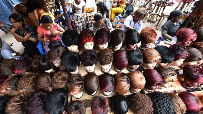 Женщины делают парики с искусственными волосами в магазине париков на рынке в Абиджане, Кот-д'Ивуар