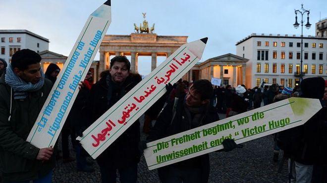 Participants hold placards in the shape of pens with a quotation of French novelist Victor Hugo