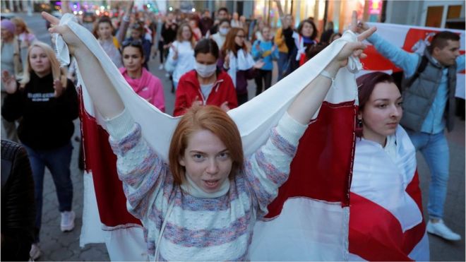 A woman carries a historical white-red-white flag of Belarus during an opposition demonstration against presidential election results in Minsk.