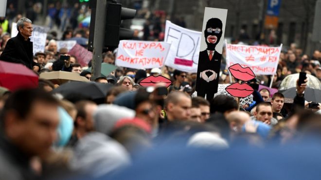 Протестующий держит карикатуру на Александра Вучича во время антиправительственной акции протеста в Белграде 8 апреля