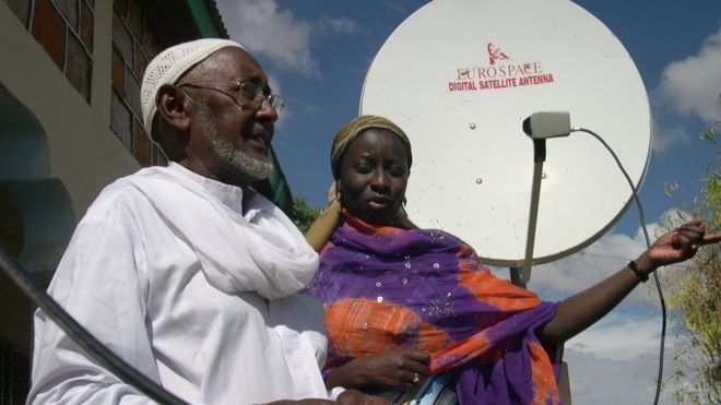Мужчина и женщина в Сомалиленде стоят перед спутниковой антенной.