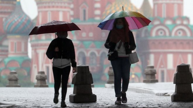 People walk under umbrellas in Red Square on 29 May 2020