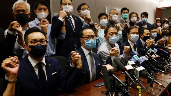 Pro-democracy lawmakers hold hands in front of the media as they resign en masse in Hong Kong