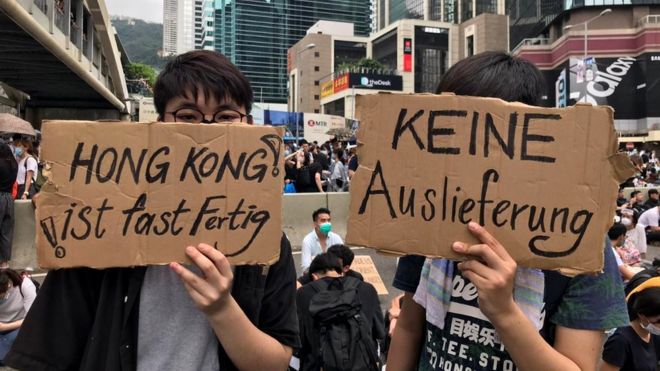 Два протестующих держат в руках плакаты, выступающие против законопроекта