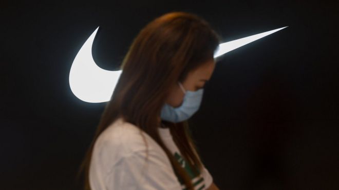 Mulher caminhando na frente de símbolo da Nike