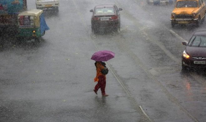 Женщина пытается управлять зонтиком между бурей и ливнем на улице в Калькутте, восточная Индия, 23 мая 2016 года.