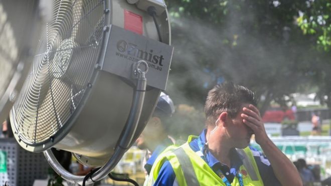 Hombre tratando de refrescarse al lado de un ventilador, en Australia.