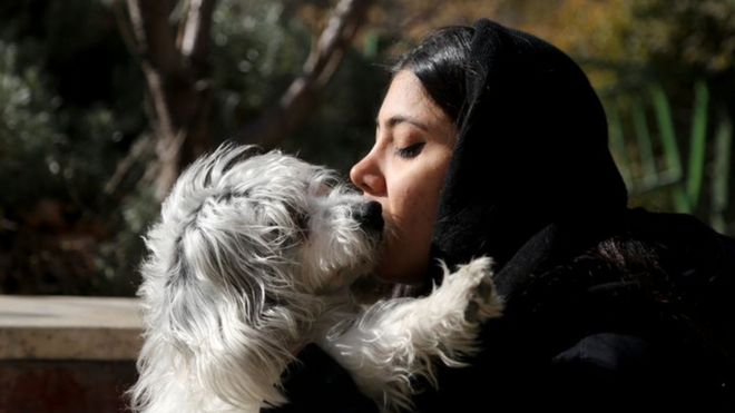 A young Iranian woman kisses her dog
