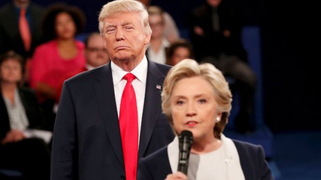 Donald Trump listens as Hillary Clinton answers a question during presidential debate at Washington University in St Louis, Missouri, U.S., October 9, 2016