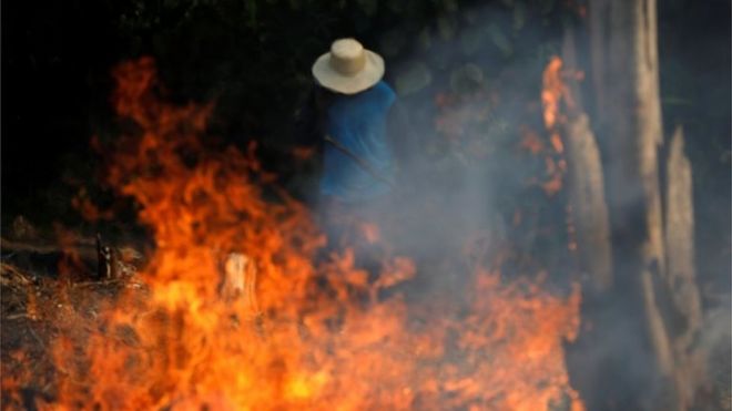 Homem diante de fogo na Amazônia