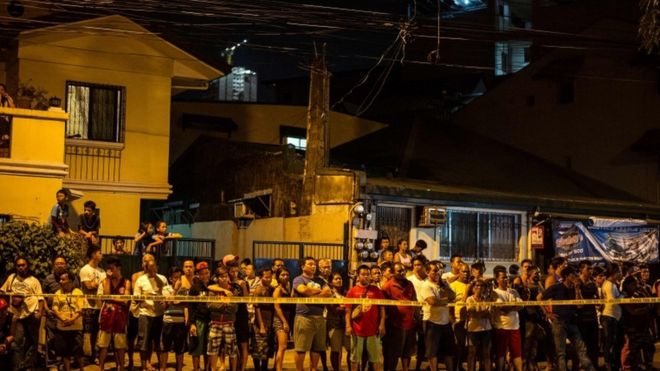 Жители района Манилы на месте перестрелки, в результате которой погибли двое подозреваемых наркоторговцев