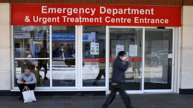 Мужчина в защитной маске проходит мимо входа в отделение неотложной помощи и Центр неотложной помощи больницы Челси и Вестминстер в центре Лондона, 23 марта 2020 г.,