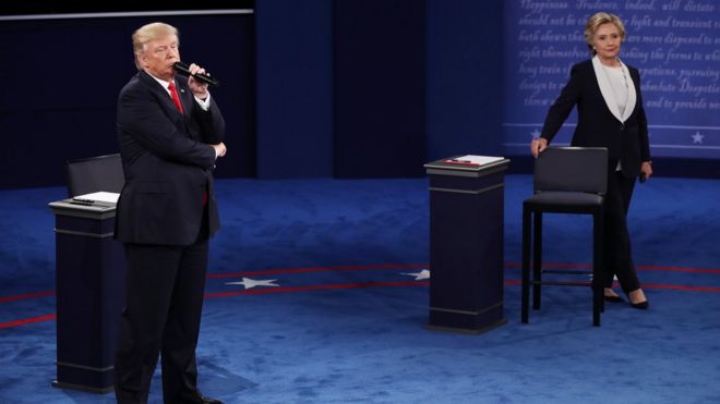 Кандидат в президенты США от республиканцев Дональд Трамп смотрит, как кандидат в президенты от Демократической партии США Хиллари Клинтон выступает во время дебатов в президентской ратуше в Вашингтонском университете в Сент-Луисе, штат Миссури, США, 9 октября 2016 года.