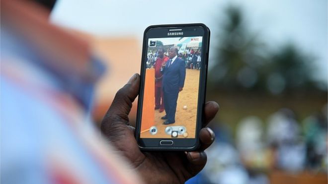 Сторонник фильма снимает на смартфон бывшего премьер-министра Ивуарии и кандидата на предстоящие президентские выборы Чарльза Конана Банни во время митинга 10 октября 2015 года в Абиджане.