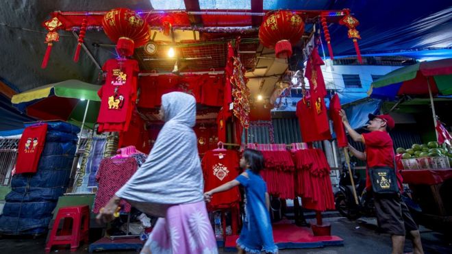 People walk past a kiosk selling Chinese-style decorations and T-shirts for the Lunar New Year in Jakarta on February 16, 2018