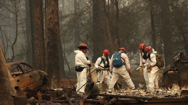Rescue workers search for human remains at a home that was burned by the Camp Fire