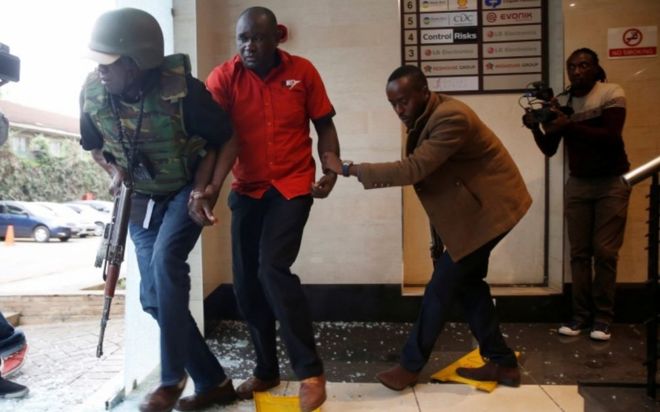 Мужчина был эвакуирован сотрудником сил безопасности на месте происшествия, где были слышны взрывы и выстрелы в гостиничном комплексе Dusit в Найроби, Кения, 15 января 2019 года.