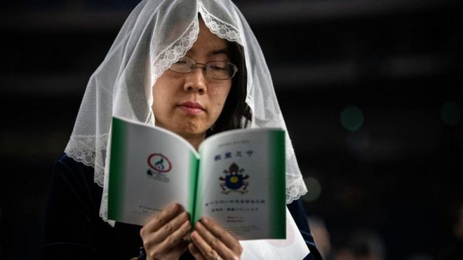 Una mujer católica lee una guía mientras espera a la misa masiva oficiada por el papa Francisco en Tokio el 25 de noviembre de 2019.