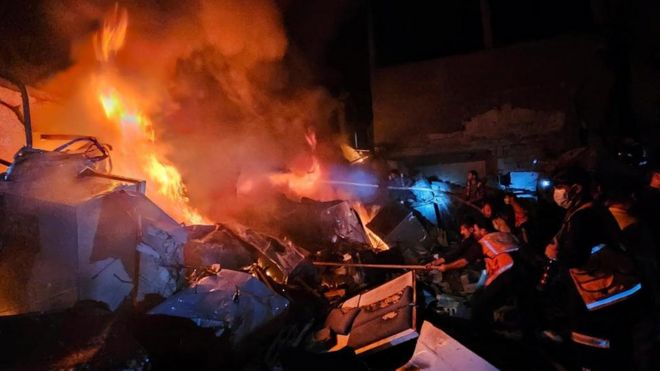 イスラエルの空爆で燃え上がるジャバリア難民キャンプの建物を、消火しようとするパレスチナ人たち（4日、ガザ地区北部）