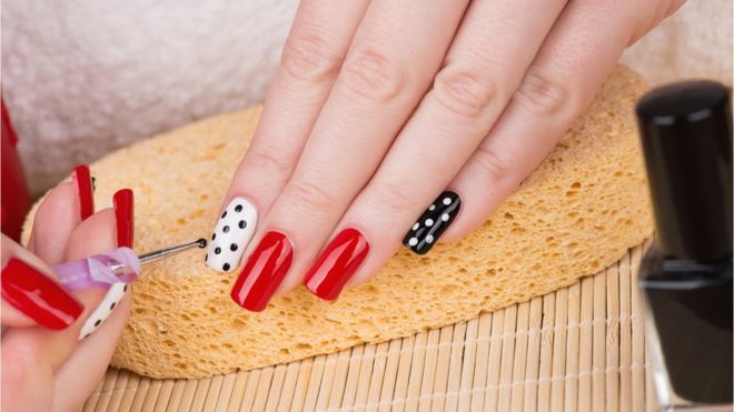 Nail Enamel Application applying nail art to hands with red white and black nail polish