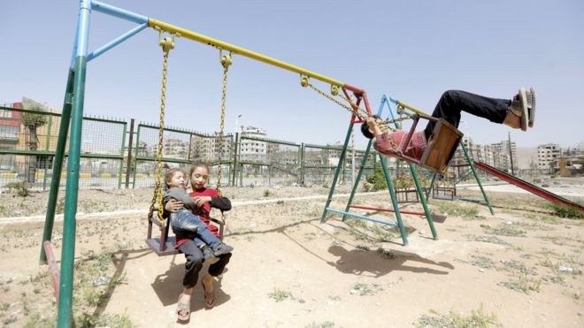 Children play on swings in Douma, 20 April