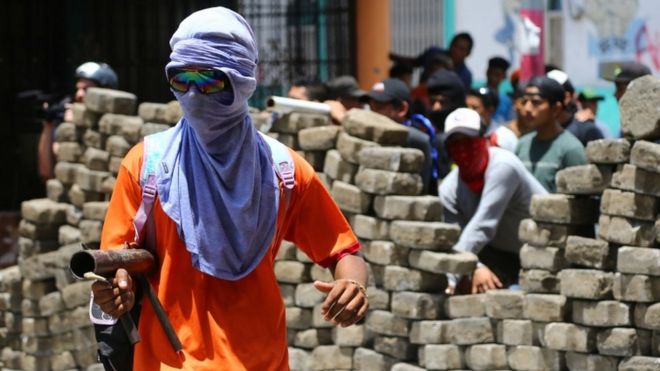 Демонстрация в маске вступает в конфликт с полицией по охране общественного порядка во время акции протеста против правительства президента Никарагуа Даниэля Ортеги в Масая, Никарагуа, 2 июня 2018 года