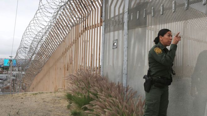 Агент пограничной службы США разговаривает через забор в Сан-Диего, штат Калифорния.