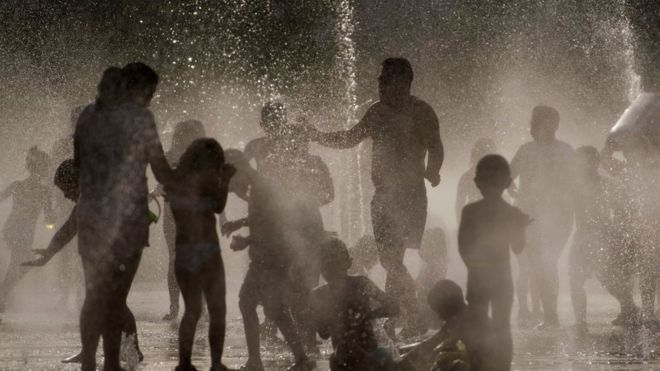 Люди охлаждаются в фонтане в Мадриде.