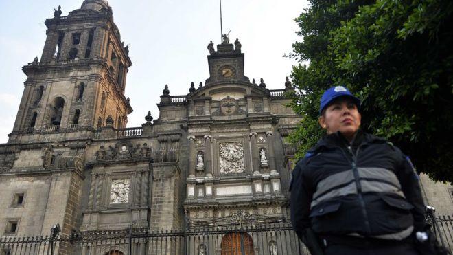 Una mujer policía frente a la entrada de la catedral metropolitana de Ciudad de México.