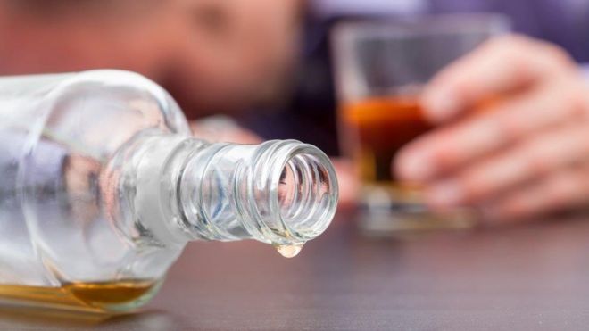 Бутылка алкоголя и рука со стаканом
