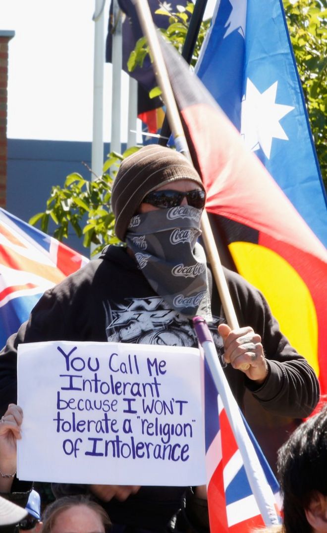 Протестующий против ислама носит маску во время протеста в Виктории