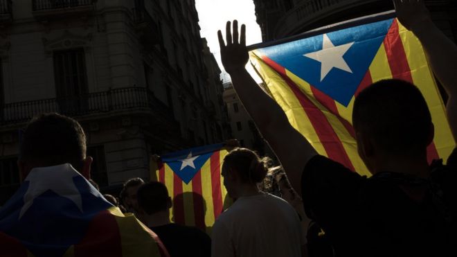 : Protesters hold up flags as they gather outside the "General Direction of the National Police of Spain", offices as Catalonian police officers surround the building on October 2, 2017