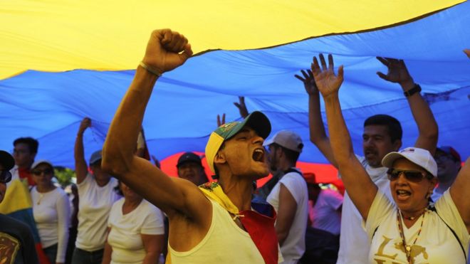 Manifestante embaixo da bandeira da Venezuela