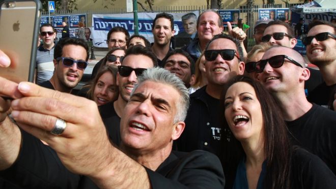 Депутат израильского парламента и председатель правоцентристской партии «Еш Атид» Яир Лапид делает селфи со своей женой Лихи и его сторонниками возле избирательного участка 17 марта 2015 года в Тель-Авиве