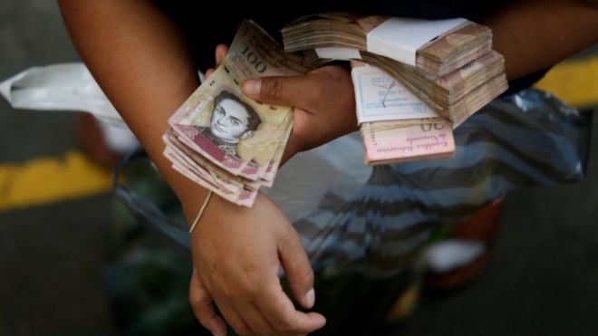 Мужчина держит груды венесуэльских банкнот