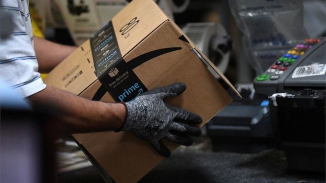 Работник собирает коробку для доставки в фулфилмент-центре Amazon.