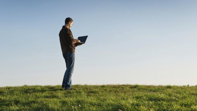 Человек, использующий ноутбук в поле