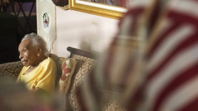 Оливия Хукер, 103 года, позирует для портрета 8 августа 2018 года в ее доме Белых равнин. Хукер - один из последних выживших свидетелей гонок в Талса в 1921 году,